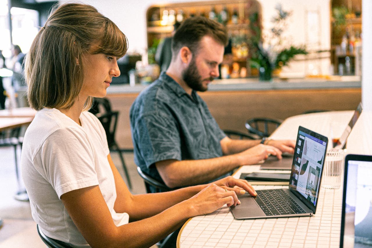 Crafting Captivating Headlines: Your awesome post title goes here Two young professionals working on laptops in a modern cafe setting.